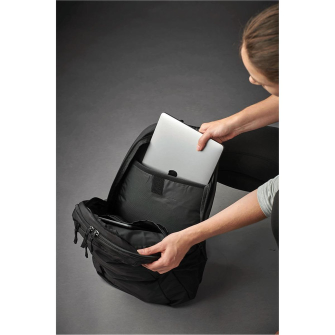 A person placing a silver laptop into a black laptop bag, featuring a sleek design and multiple compartments.