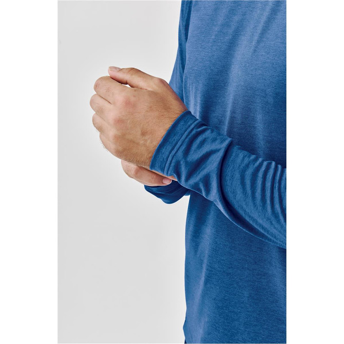 A close-up of a man's hand adjusting the sleeve of a blue long-sleeve crew neck shirt, featuring a logo.