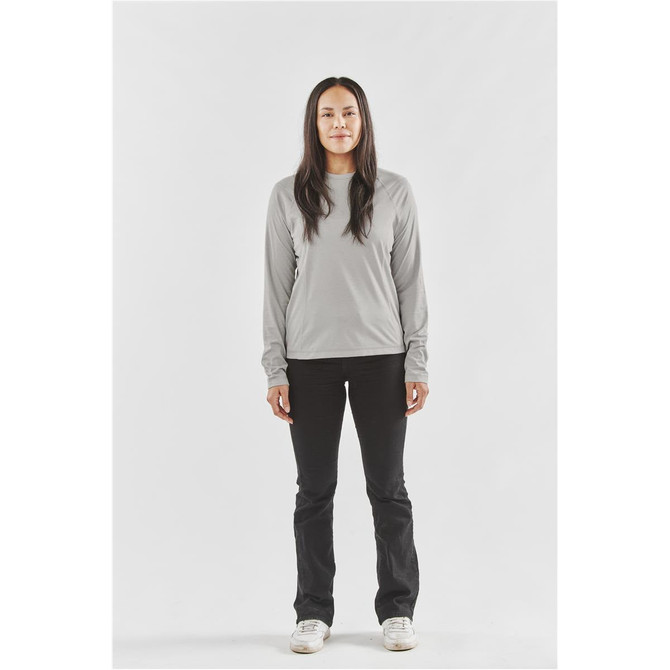 A long-sleeve women's t-shirt in light grey, paired with black pants and white shoes, featuring a logo.