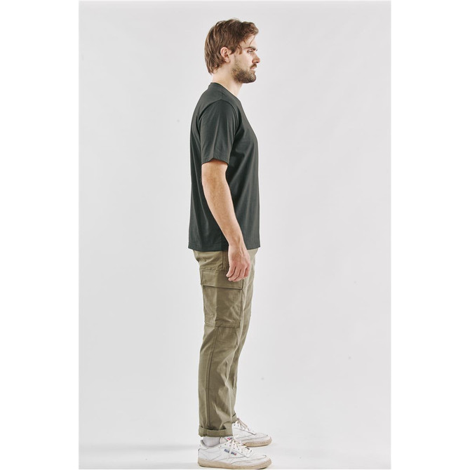 A side view of a man wearing a black Men's Settebello Tee paired with olive green trousers and white sneakers.