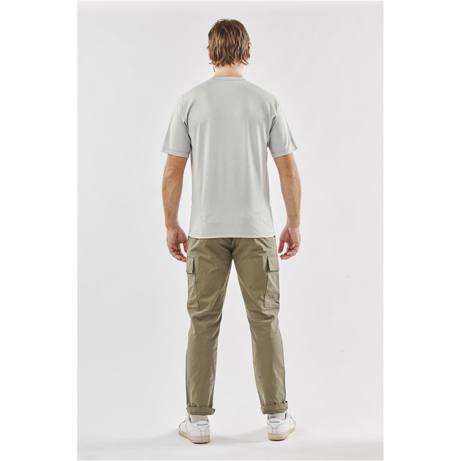 A man wearing a light grey T-shirt and khaki pants, standing with his back to the camera. The shirt features a logo.