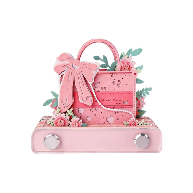 A pink 3D paper art handbag-shaped notepad adorned with floral designs and a decorative bow. It features a silver base.