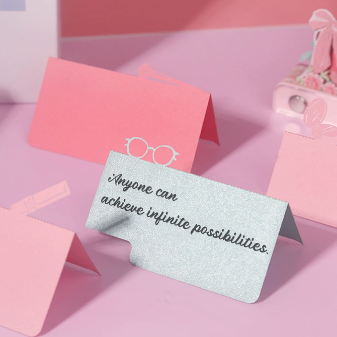 A collection of decorative, colourful notepads in pink and silver with playful designs and motivational text.