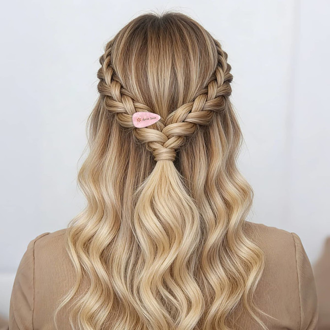 A hair style featuring intricate braids with a pink teardrop iridescent alligator hair clip holding a half-up section.