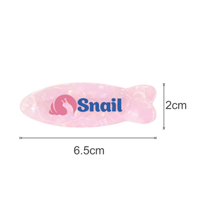 A fish-shaped iridescent hair clip in pink with a logo. Dimensions are 6.5 cm long and 2 cm wide.