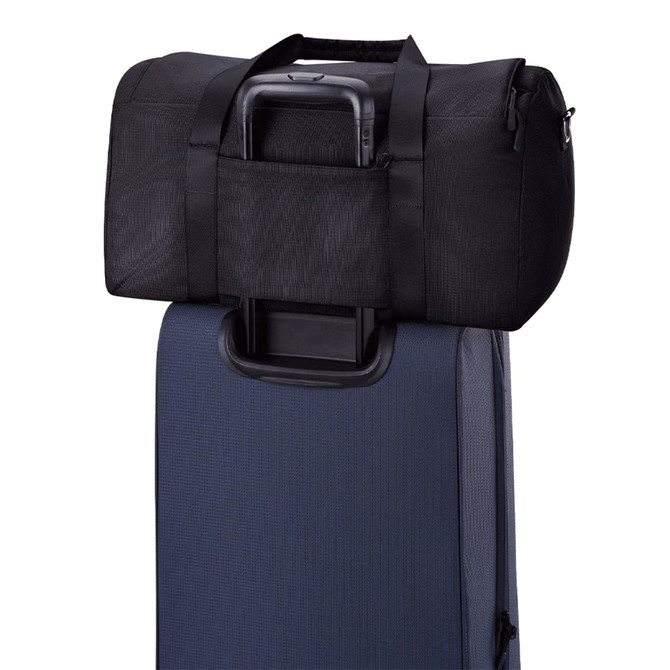 A black duffel bag rests on top of a dark blue suitcase, featuring straps and a handle.