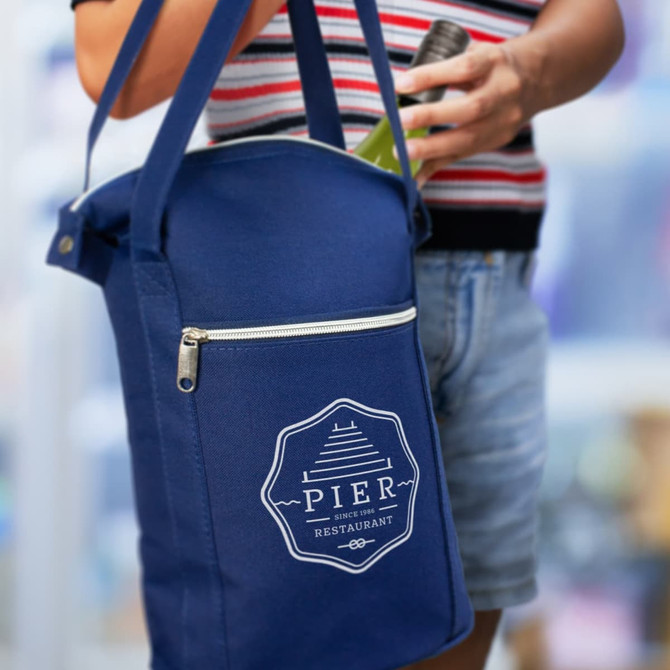 A drink bottle is held next to a navy cooler bag featuring a logo and a zippered pocket.