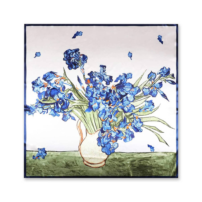 A silk satin scarf featuring a floral design with vibrant blue irises in a vase against a light background.
