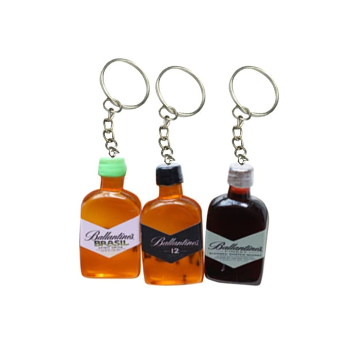 Three custom-shaped resin keychains resembling miniature whisky bottles in amber, dark brown, and a clear bottle with a green lid.