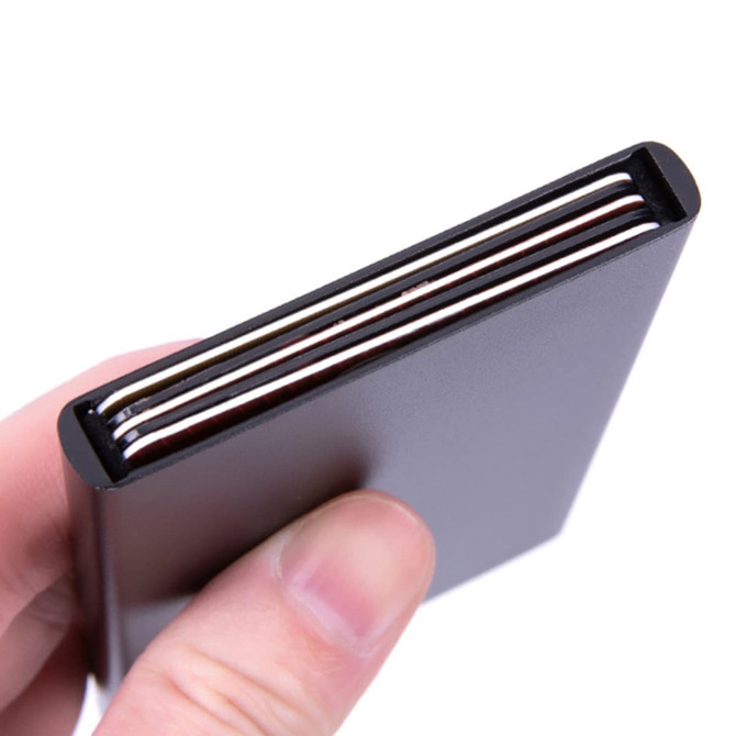 A hand holding a sleek black metal RFID card holder with several cards visible inside.