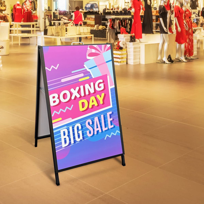 A metal A-frame sign with a colourful promotional design, featuring a black frame and placed in a retail environment.