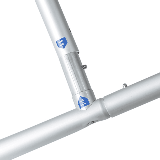 A close-up of a silver metal frame with connectors, part of a curved fabric banner stand.