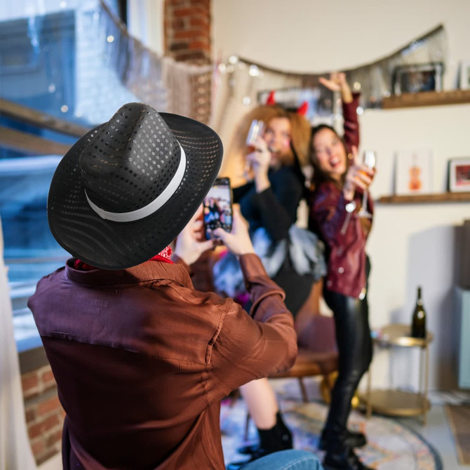 A group of people in a festive setting, wearing sequin cowboy hats in black and silver.