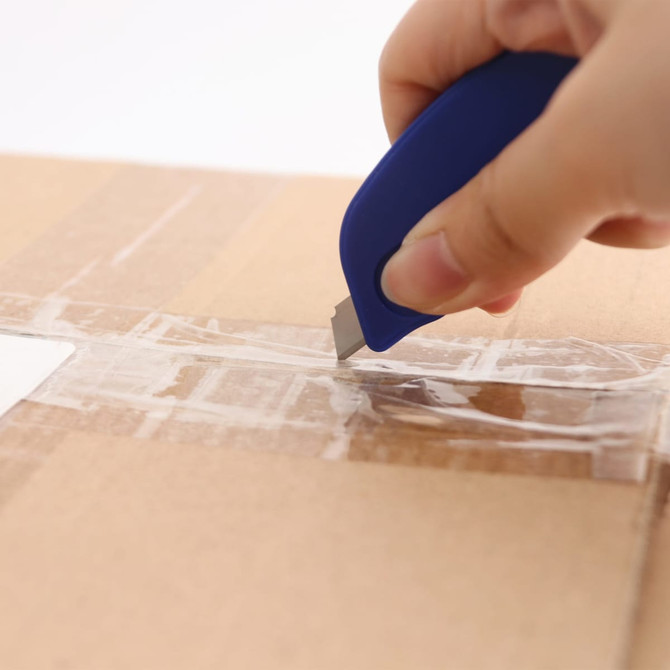 A blue mini cutter keyring is being used to cut through tape on a cardboard box.