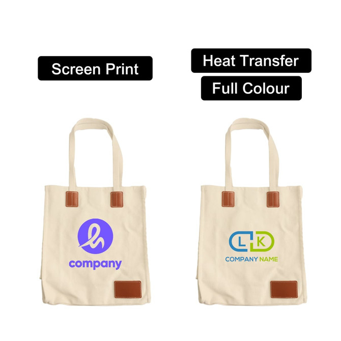 A beige canvas bag with leather handles, featuring a logo on each side and a magnetic snap closure.