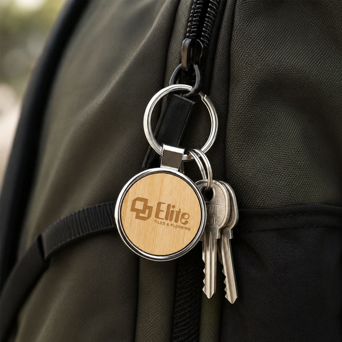 A round wooden keyring with a silver metal ring, attached to a dark green backpack alongside keys.