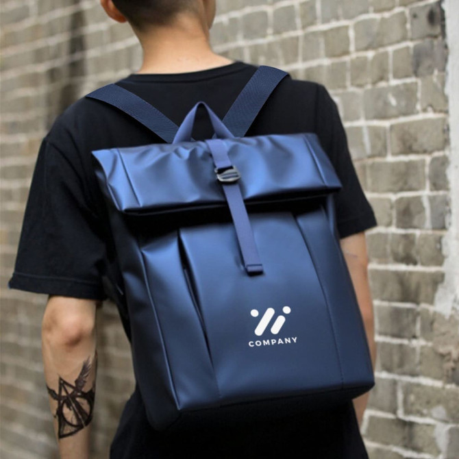 A navy tarpaulin roll top backpack worn on a person’s back, featuring a logo and adjustable straps.