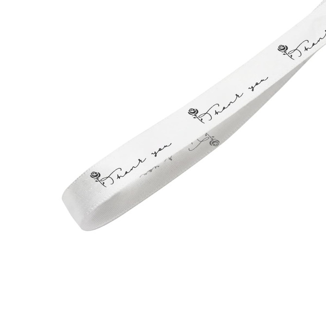 A white cotton ribbon featuring black printed text and a rose design, with a logo on the side.