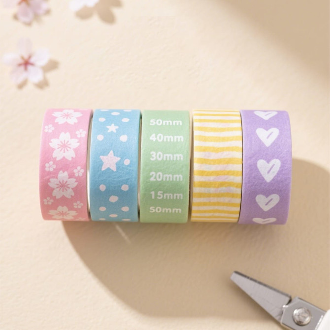 Five rolls of washi tape in pastel colours: pink with flowers, blue with stars, green, yellow striped, and purple with hearts.