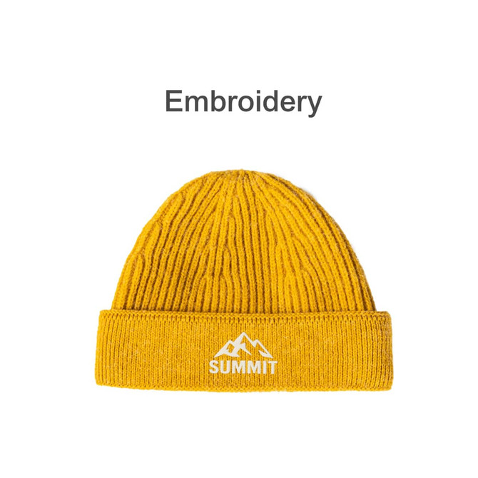 A round, yellow beanie with a ribbed design and a logo featuring mountains and text on the cuff.
