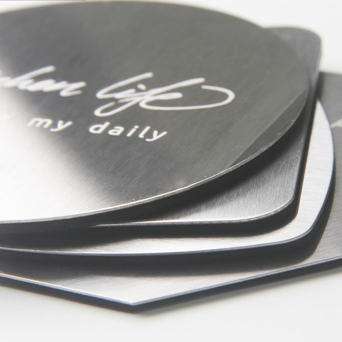 An octagonal metal coaster set featuring a shiny silver finish, stacked with a branding logo visible on top.