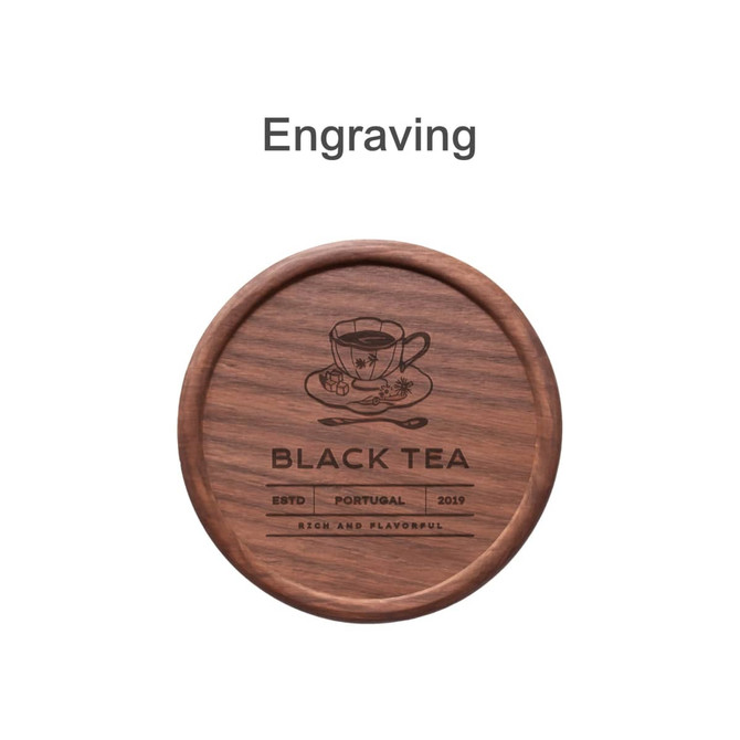 A round wooden coaster featuring an engraved design with a tea cup and branding elements. The colour is a rich brown.