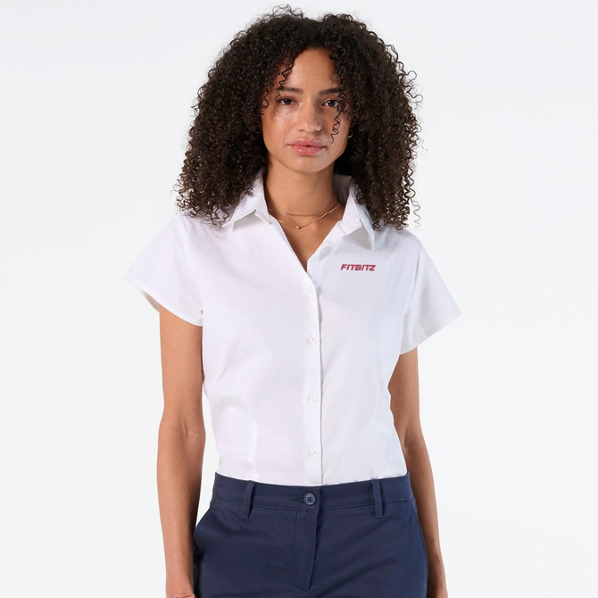 A white short sleeve button-up shirt with a collar and a logo on one side, styled on a model.