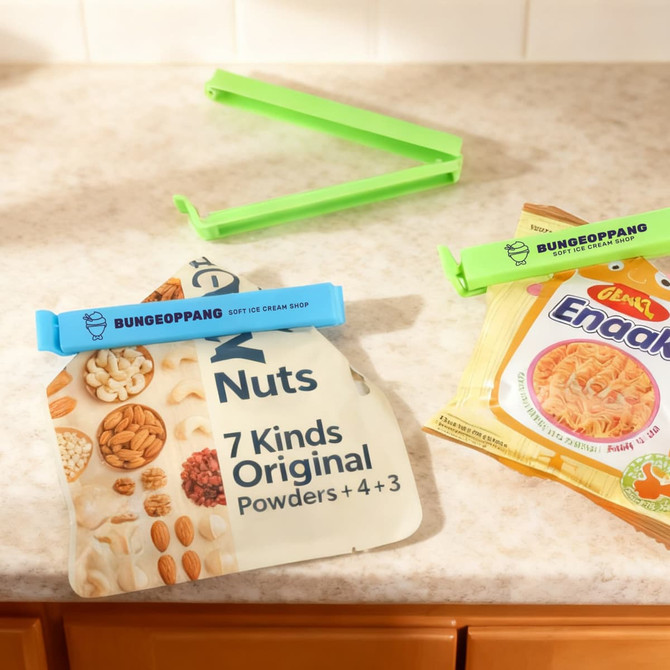 A blue and a green food bag seal clip on packaging, with a variety of nuts and a snack product in the background.