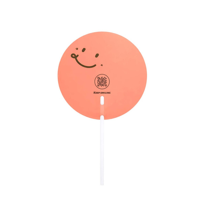 A round, orange hand fan with a smiling face design and a white handle, featuring a logo and text.