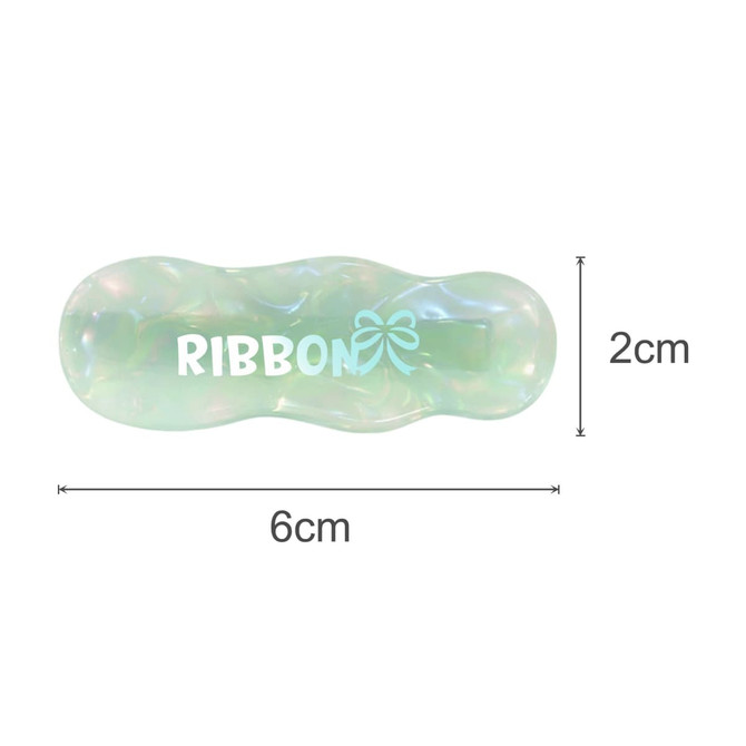A ripple iridescent alligator hair clip in green and clear colours, featuring a logo in white. Dimensions are 6cm x 2cm.