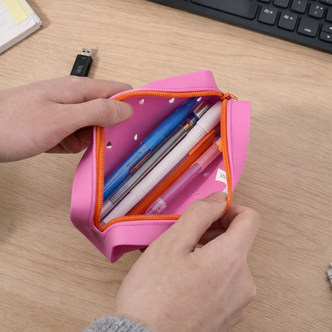 A pink silicone pencil case with an orange zipper, containing various pens and a USB drive inside.