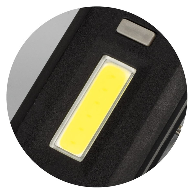 A close-up of a black key ring light featuring a bright yellow COB LED strip and a metal button.