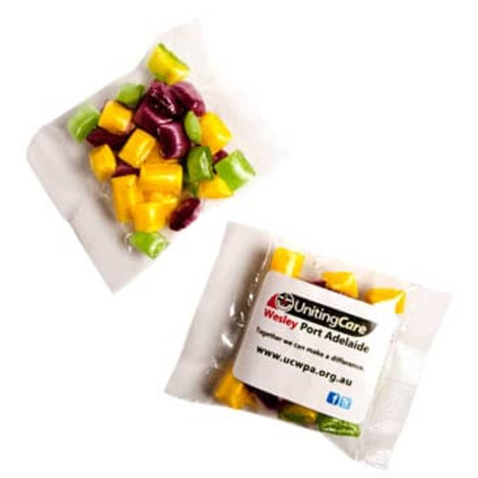 A sealed packet of assorted humbugs in vibrant green, yellow, and purple colours, with a logo and branding visible.