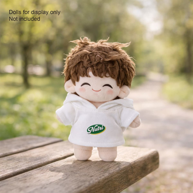 A plush doll wearing a white hoodie with a branded logo and brown hair, set in a natural outdoor environment.