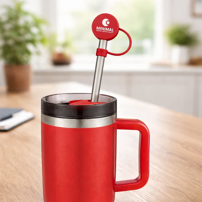 A drink bottle with a red silicone straw cover and a stainless steel straw, set on a table with a plant in the background.