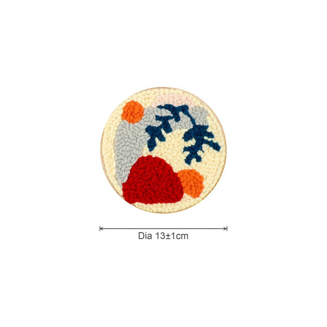A round coaster featuring a colourful punch needle design with grey, red, orange, and blue elements, measuring 13 cm in diameter.