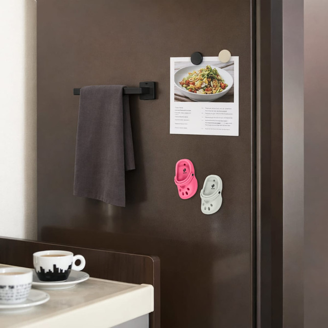 Paw shape clog shoe fridge magnets in pink and white, displayed on a dark fridge alongside a towel and an image.