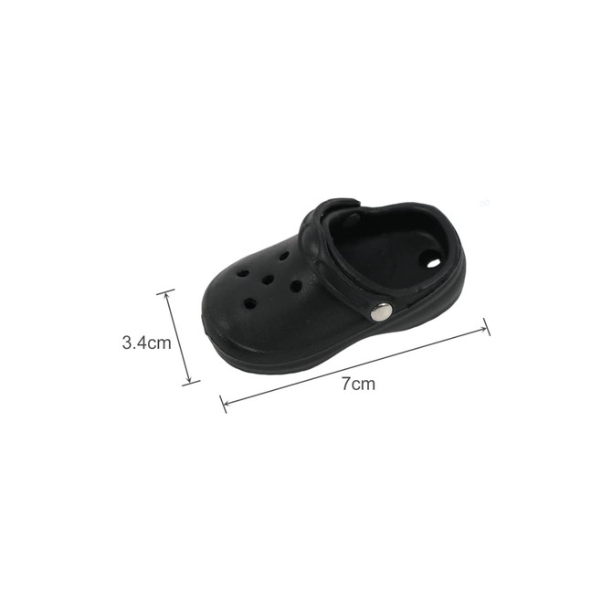 A small black clog shoe fridge magnet, featuring ventilation holes and a strap, measuring 7 cm by 3.4 cm.