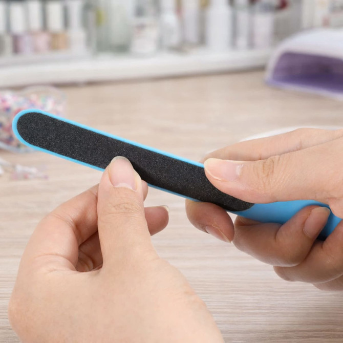 A nail file with a blue handle and a black filing surface is being held in a person's hand.