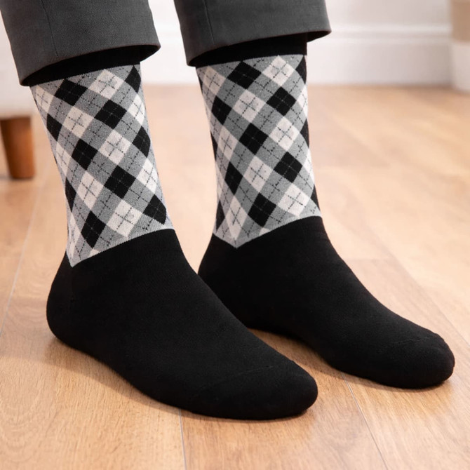 A pair of black socks with a grey and black argyle pattern woven on the upper section, worn with trousers.