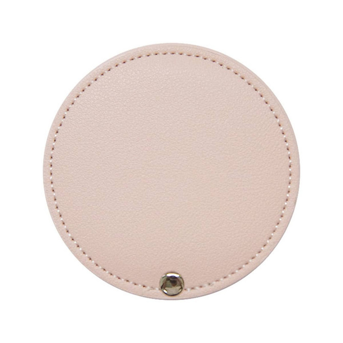 A round makeup mirror in a soft pink colour with a stitched edge and a metal button detail.