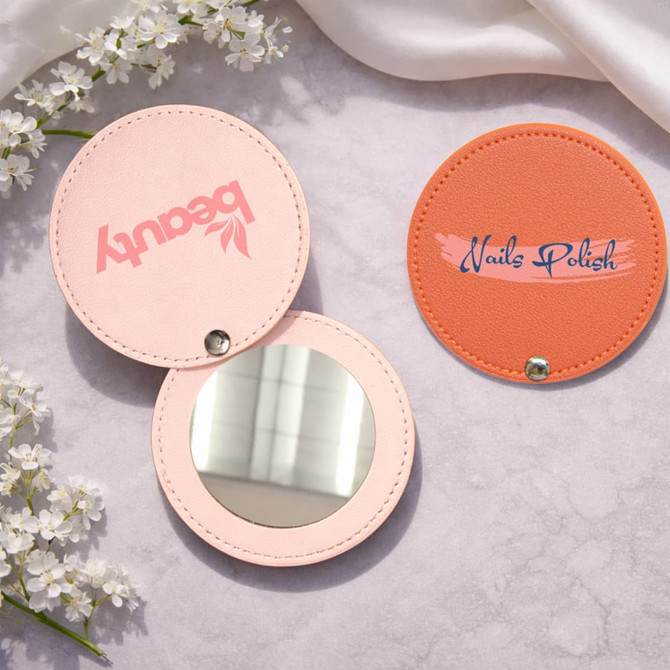A round makeup mirror with a light pink exterior and a vibrant orange exterior, featuring logos on each side.