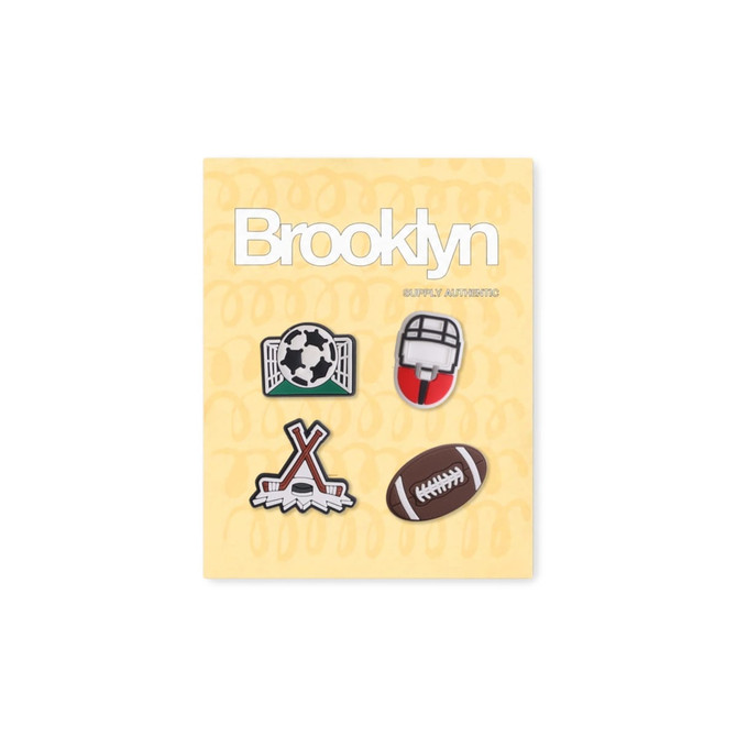 A pack of four custom shoe charms featuring sports designs: soccer, football, hockey, and a helmet, on a yellow background.