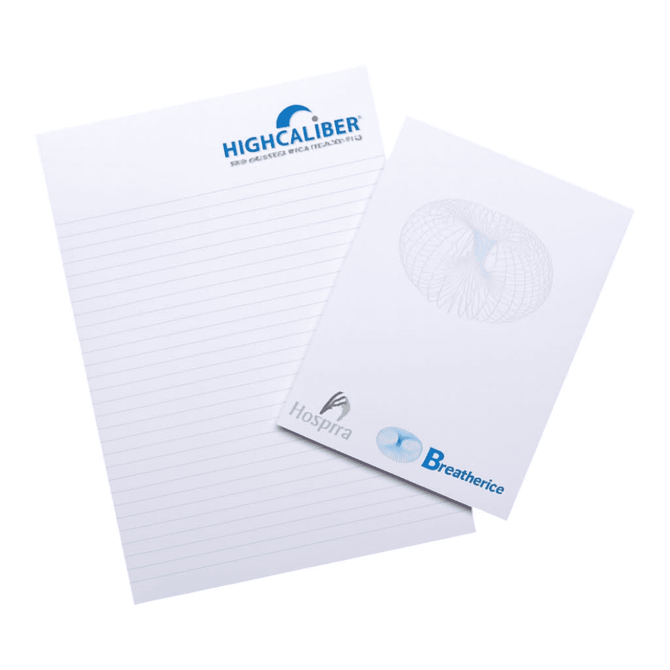 A notepad featuring lined pages, with a logo on the top and a smaller pad beside it, on a wooden surface.