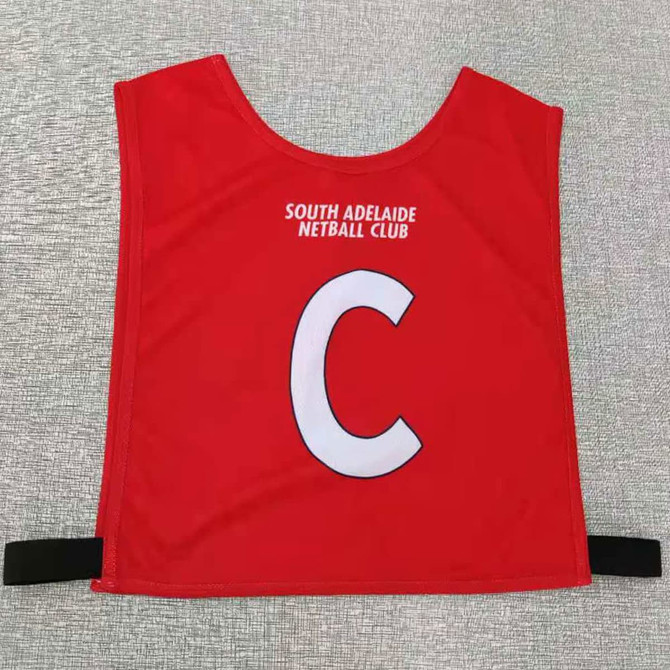 Red elastic netball bib featuring a large white 'C' and a logo from South Adelaide Netball Club.