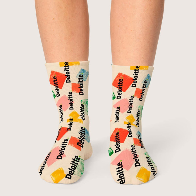 Colourful socks featuring various shapes and a logo pattern in green, yellow, red, and blue against a cream background.