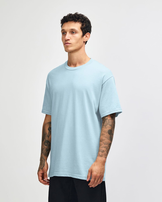 A light blue heavyweight cotton unisex t-shirt on a model, featuring a simple design and a logo.