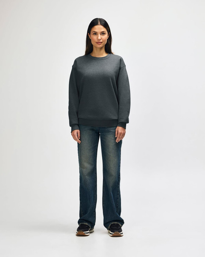 A grey Gildan Heavy Blend adult crewneck sweatshirt worn by a model, paired with black jeans and sneakers.
