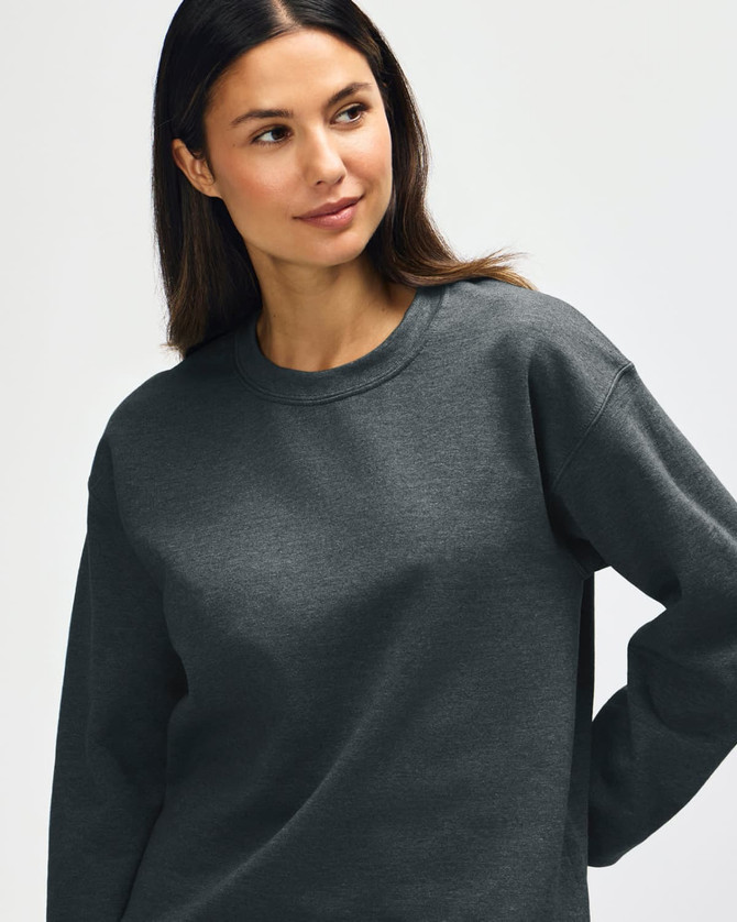 A model wearing a grey Gildan Heavy Blend Adult Crewneck Sweatshirt with long sleeves and a relaxed fit.