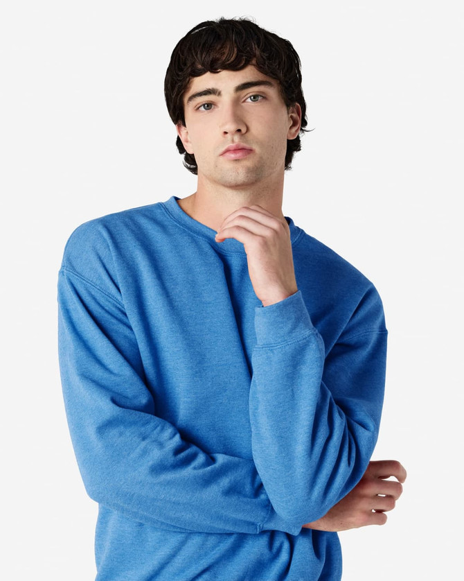 A blue Gildan Heavy Blend adult crewneck sweatshirt with a model posing in a casual setting. The sweatshirt has a logo.